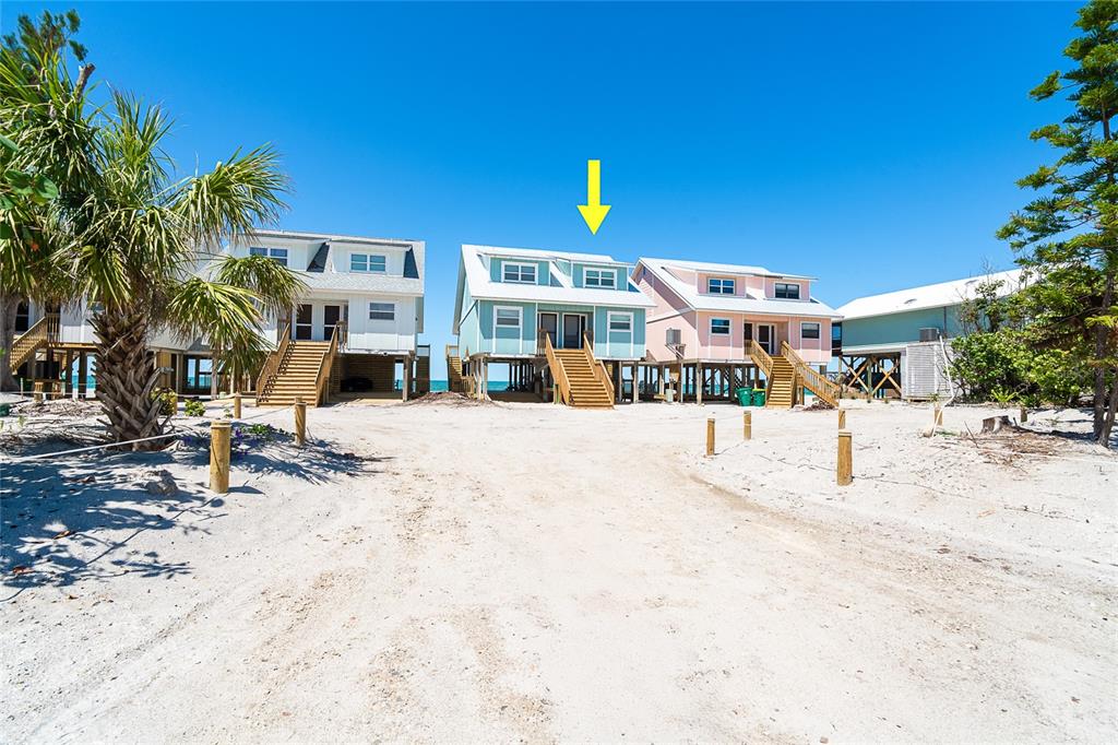 A row of elevated beach houses stands on a sandy lot under a clear sky — 301 S GULF BOULEVARD UNIT 3, PLACIDA, FL