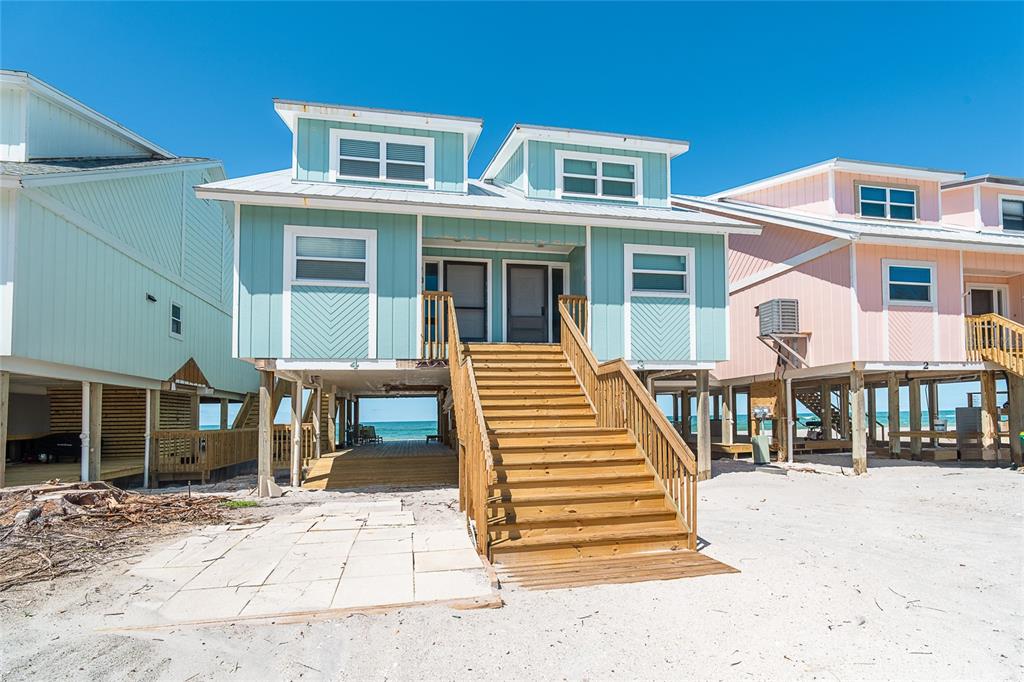 A light blue elevated beach house features a central wooden staircase leading to two doors — 301 S GULF BOULEVARD UNIT 3, PLACIDA, FL