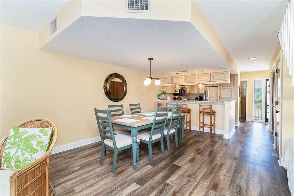 A dining area with a wooden table and blue chairs sits next to a kitchen — 301 S GULF BOULEVARD UNIT 3, PLACIDA, FL