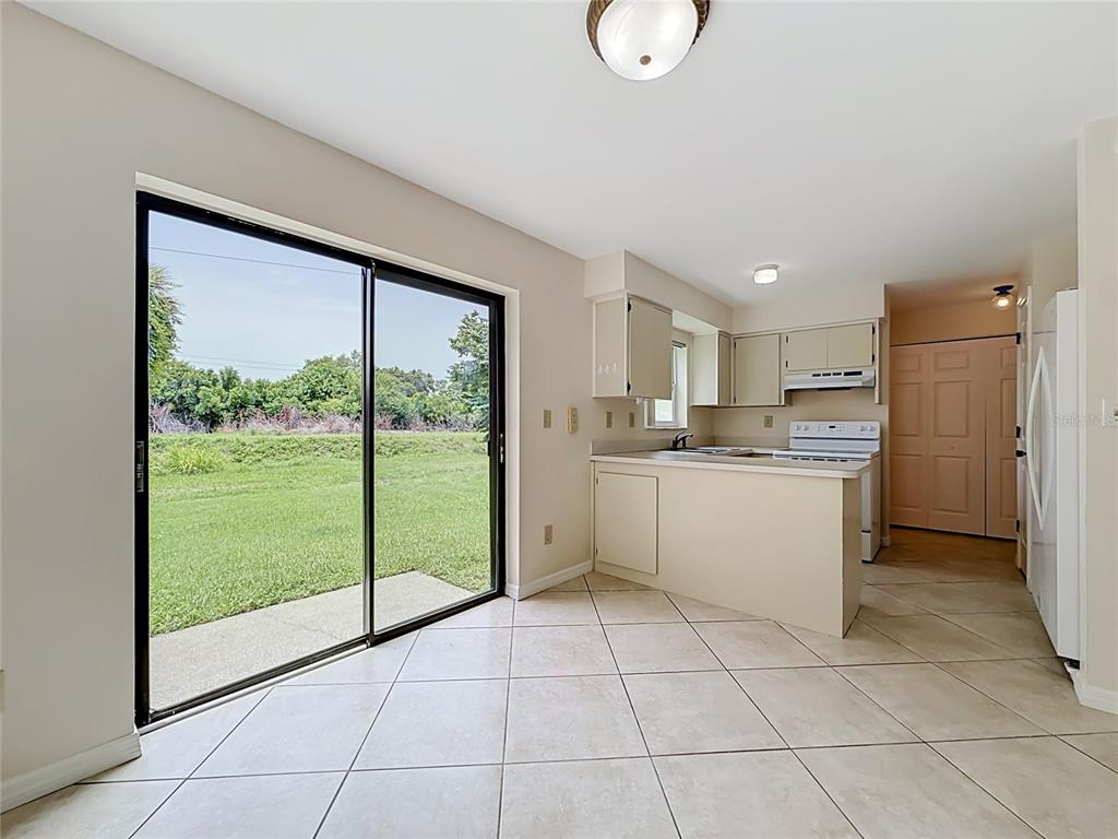 A kitchen with beige cabinets and tile flooring opens to a patio through sliding doors — 1718 ADAMS CIRCLE S, LARGO, FL