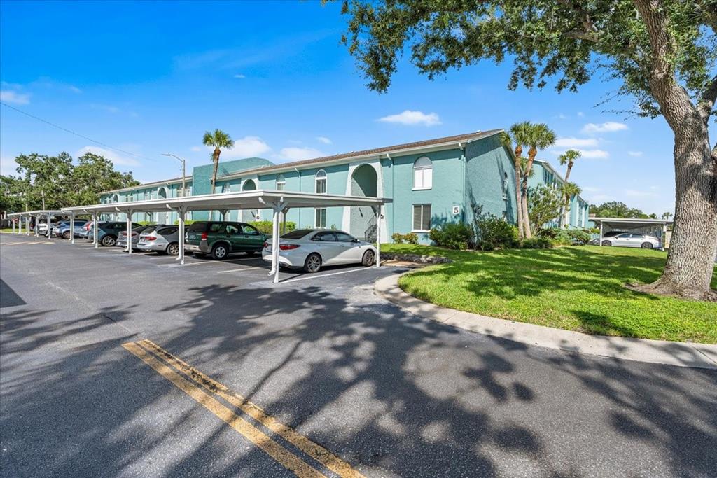 A teal apartment building with a covered parking structure and a grassy lawn — 11401 3RD STREET N UNIT 2, ST PETERSBURG, FL