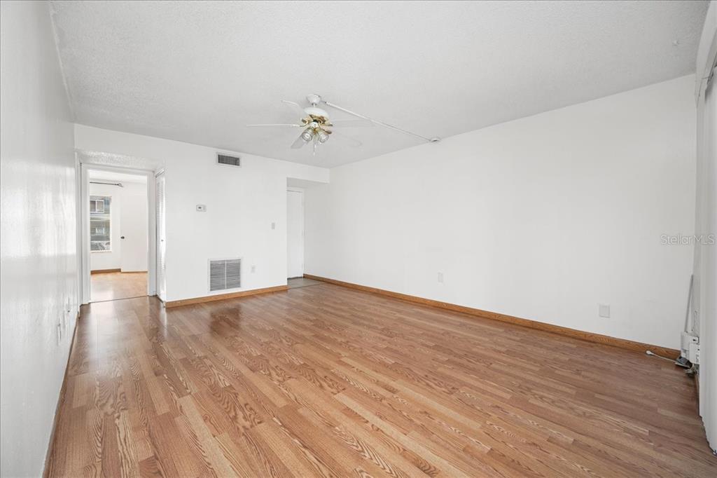 An empty living room features light wood flooring, white walls, and a ceiling fan — 11401 3RD STREET N UNIT 2, ST PETERSBURG, FL