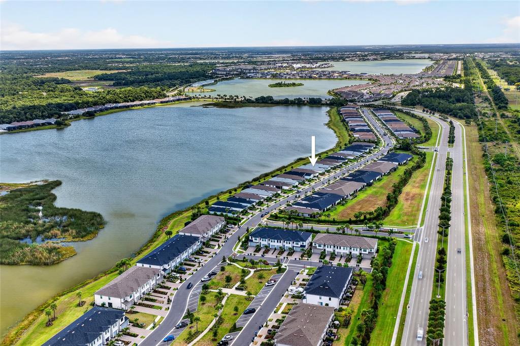 An aerial view shows a residential neighborhood of townhomes situated along a large lake — 6492 SILVERSTAR DRIVE, SARASOTA, FL