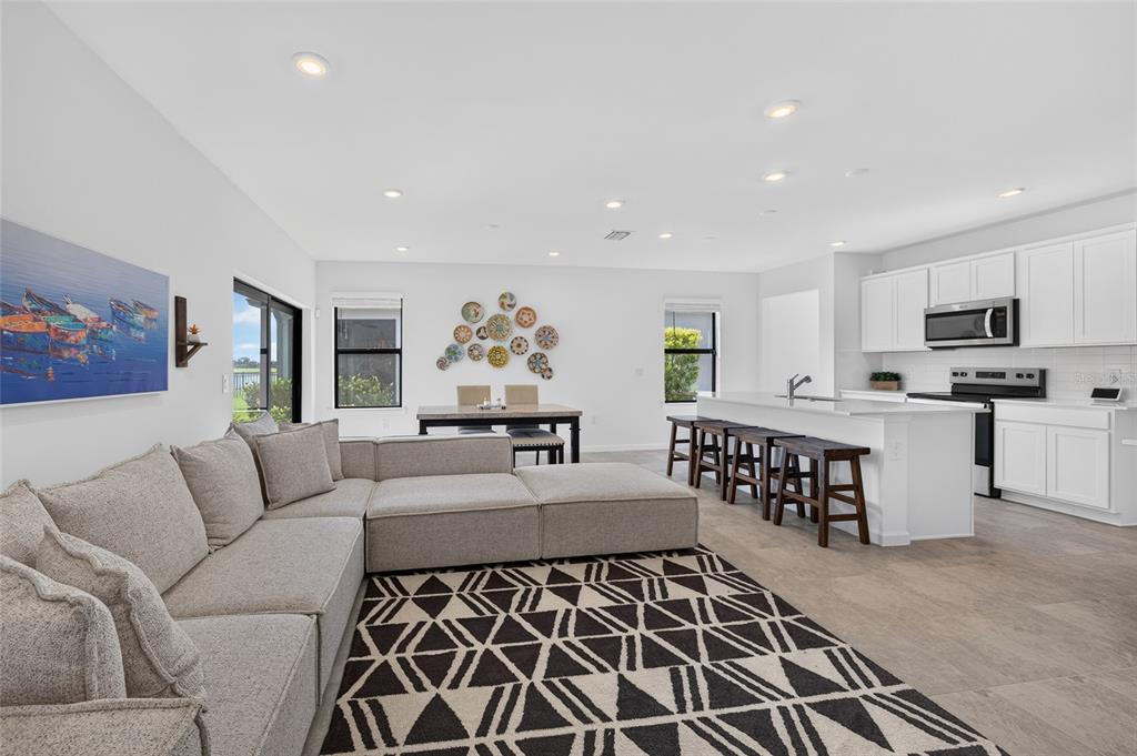 An open-concept living room, dining area, and kitchen with white cabinets and a sectional sofa — 6492 SILVERSTAR DRIVE, SARASOTA, FL