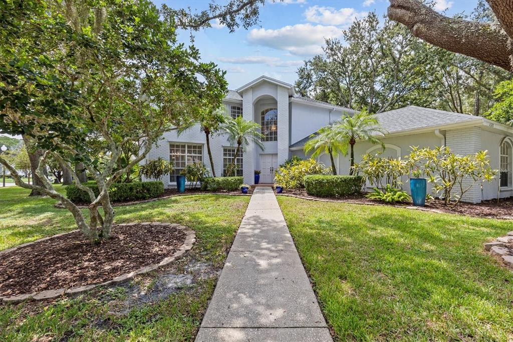 A two-story white brick house with a front walkway and mature landscaping — 2328 WARWICK DRIVE, OLDSMAR, FL