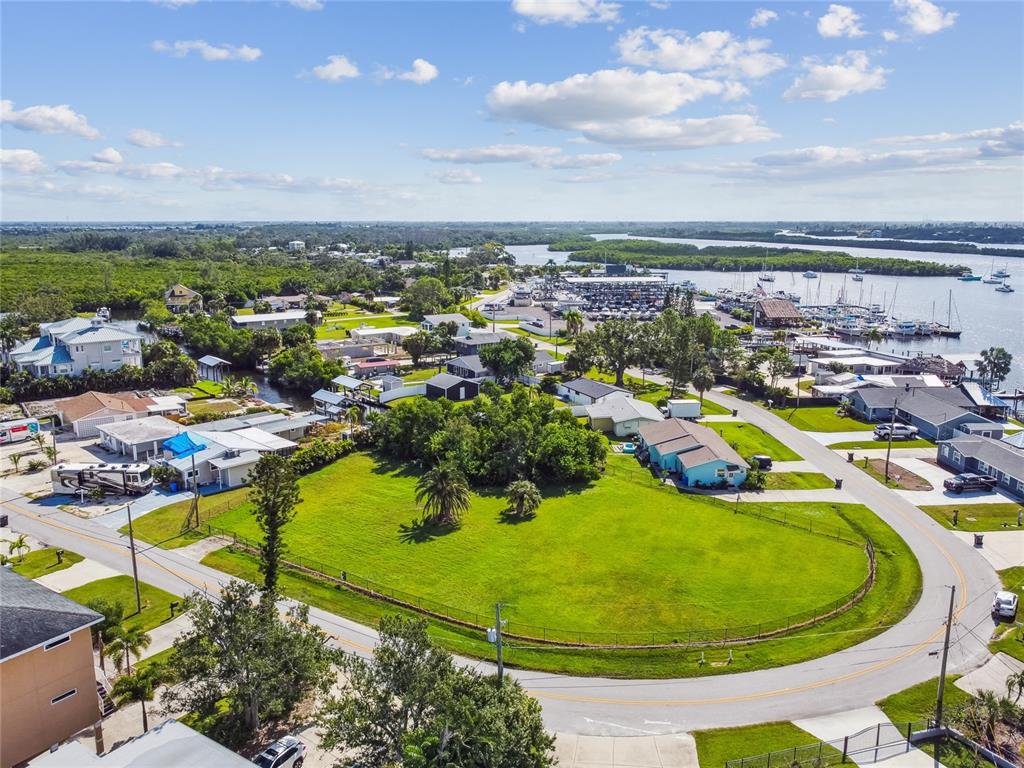 An aerial view shows a large grassy lot surrounded by a road, nearby houses, and a marina — W SHELL POINT ROAD, RUSKIN, FL