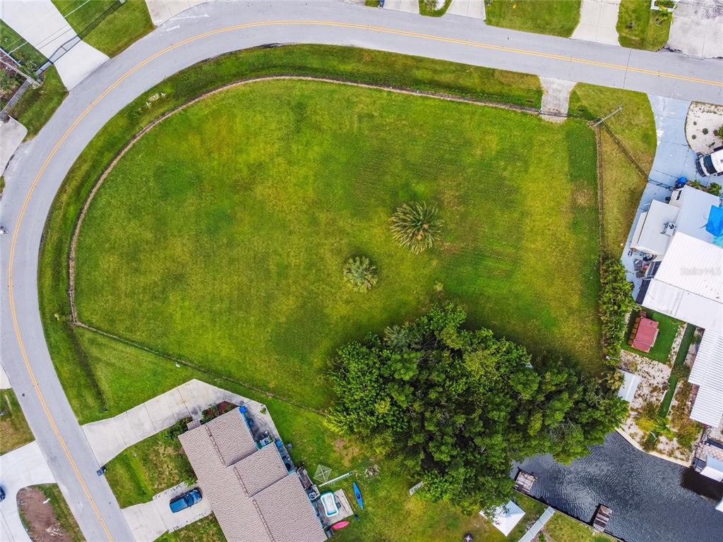 An aerial view shows a large, grassy corner lot bordered by a curved road and canal — W SHELL POINT ROAD, RUSKIN, FL