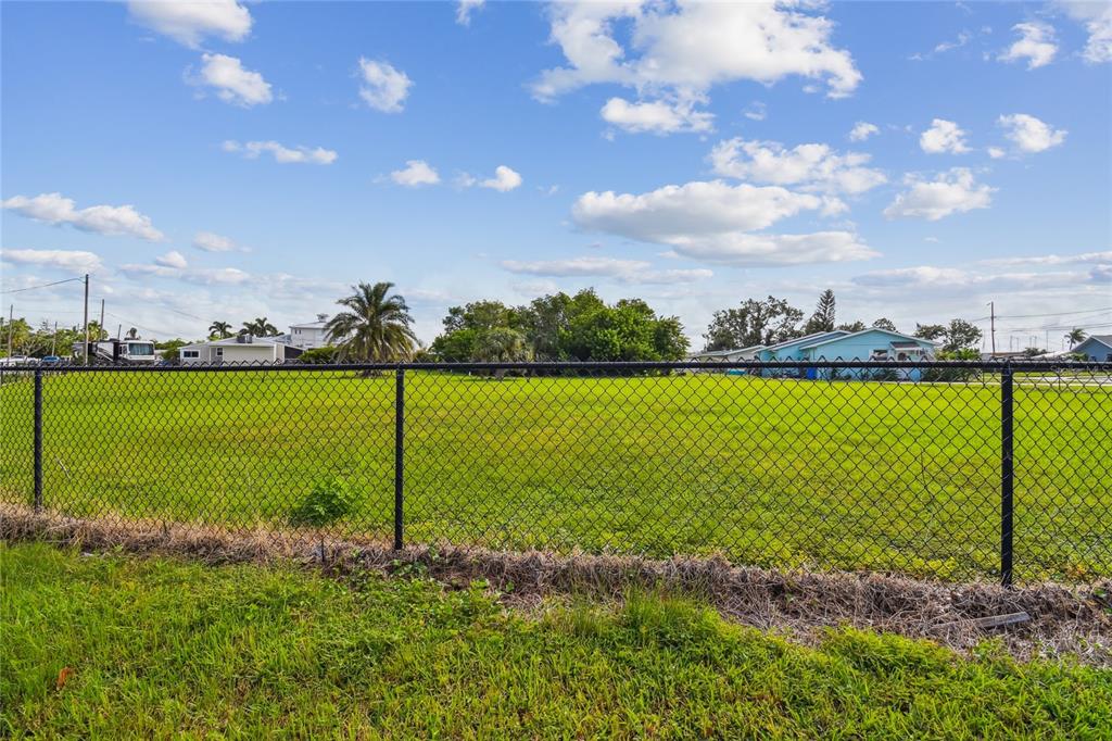 A chain-link fence encloses a large, flat, grassy vacant lot under a blue sky — W SHELL POINT ROAD, RUSKIN, FL