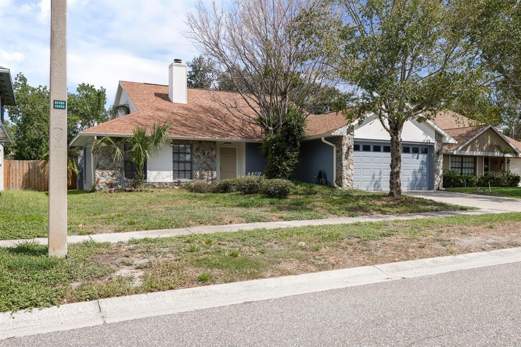 A single-story house with a stone facade, blue siding, a two-car garage, and a chimney — 1912 FIRETHORN COURT, BRANDON, FL