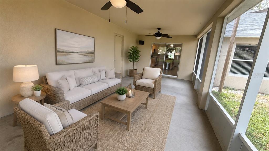 A screened-in patio features wicker furniture, a neutral rug, and a view of the backyard — 539 GRANITE CIRCLE, CHULUOTA, FL