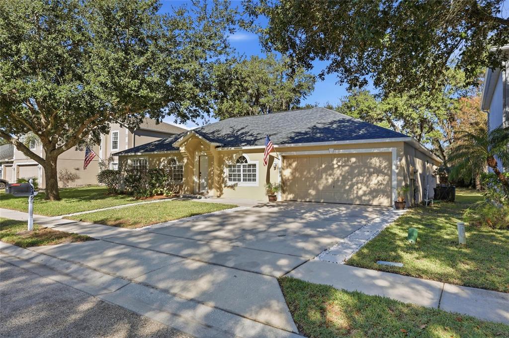 A single-story house with a tan exterior, a two-car garage, and a concrete driveway — 539 GRANITE CIRCLE, CHULUOTA, FL