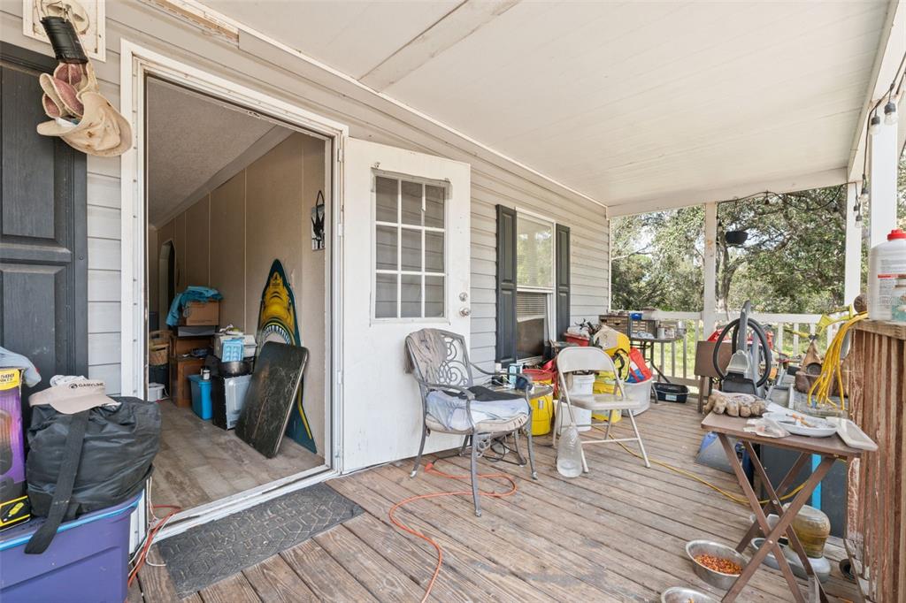 A cluttered wooden porch leads into a home through an open doorway — 17221 NICKS DRIVE, SPRING HILL, FL