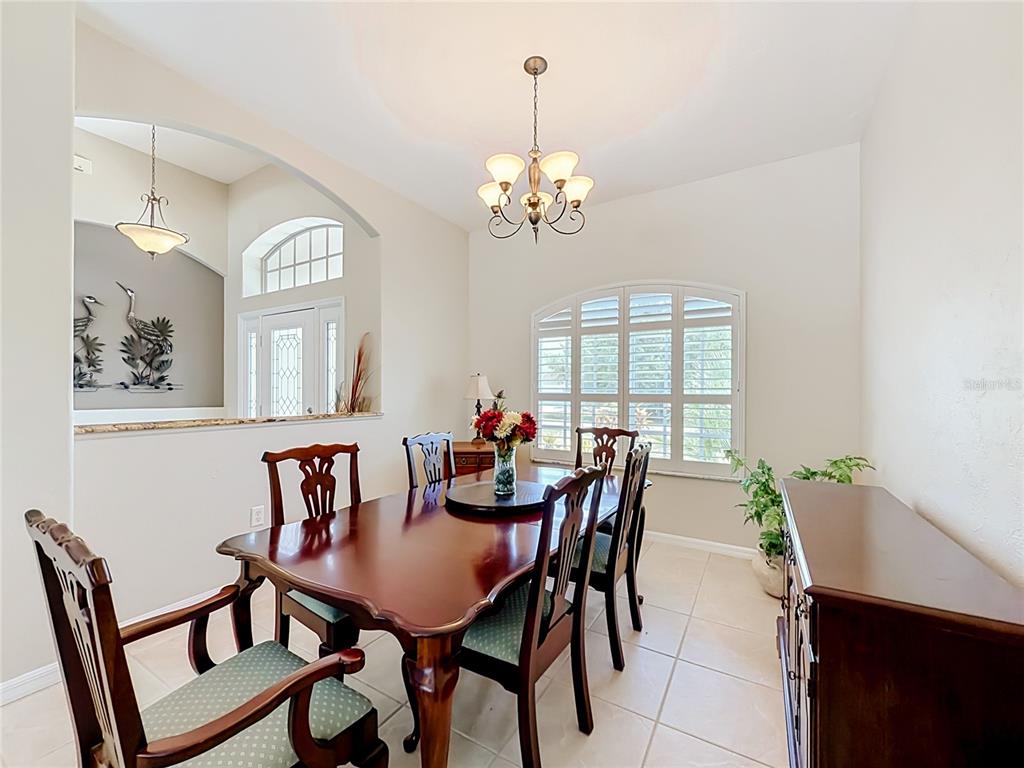 A dining room features a dark wood table, six chairs, and a matching sideboard — 27423 NATAL DRIVE, PUNTA GORDA, FL