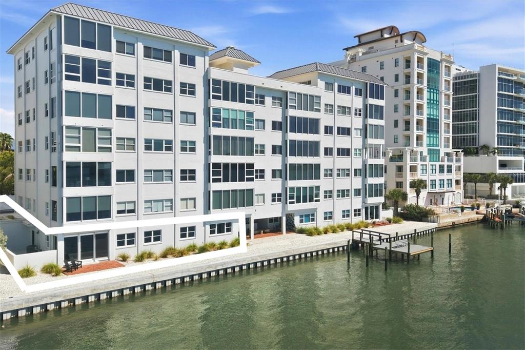 An aerial view shows apartment buildings near a bridge illuminated with red, white, and blue lights — 226 GOLDEN GATE POINT UNIT 12, SARASOTA, FL