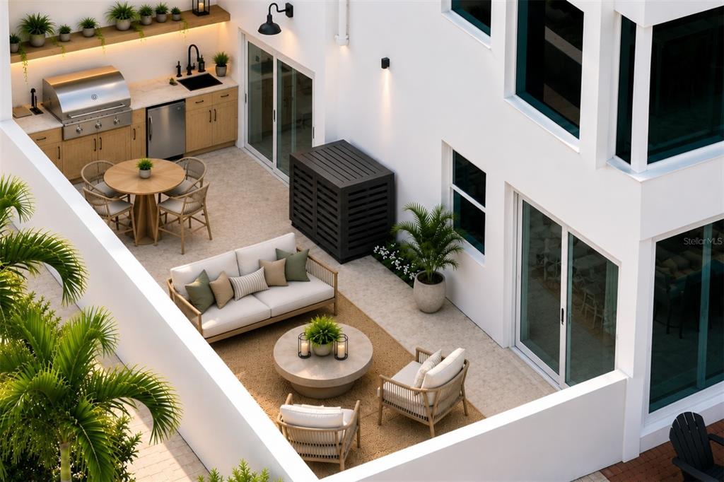 A living room with a sofa faces large sliding glass doors overlooking a sunset water view — 226 GOLDEN GATE POINT UNIT 12, SARASOTA, FL