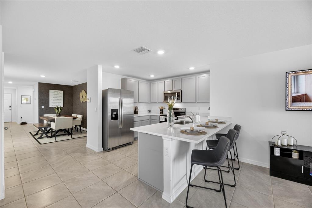 A living room features a gray sectional sofa, a ceiling fan, and sliding glass doors — 3345 BLUE ESTUARY ROAD, WIMAUMA, FL