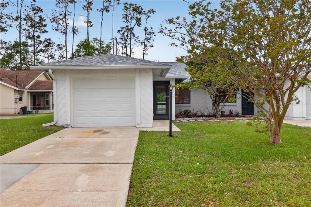 A single-story house with a white garage, a concrete driveway, and a tree in front — 10 BREN MAR LANE, PALM COAST, FL