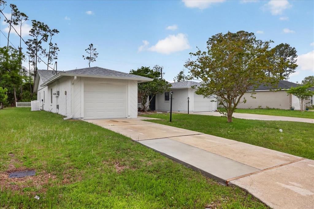A white single-story house with a garage and a concrete driveway on a grassy lot — 10 BREN MAR LANE, PALM COAST, FL