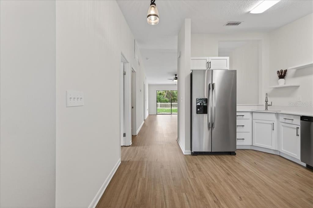 A kitchen with white cabinets and stainless steel appliances opens to a hallway and backyard — 10 BREN MAR LANE, PALM COAST, FL