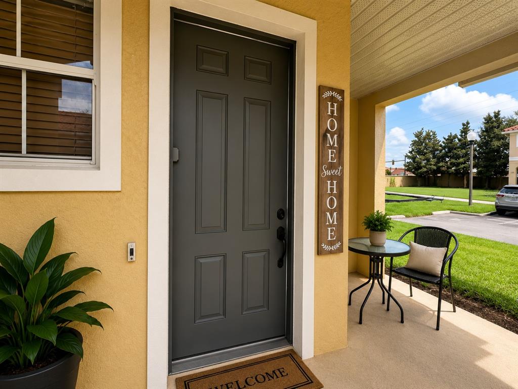 A dark gray front door sits on a yellow stucco porch next to a window — 7601 ACKLINS ROAD, KISSIMMEE, FL