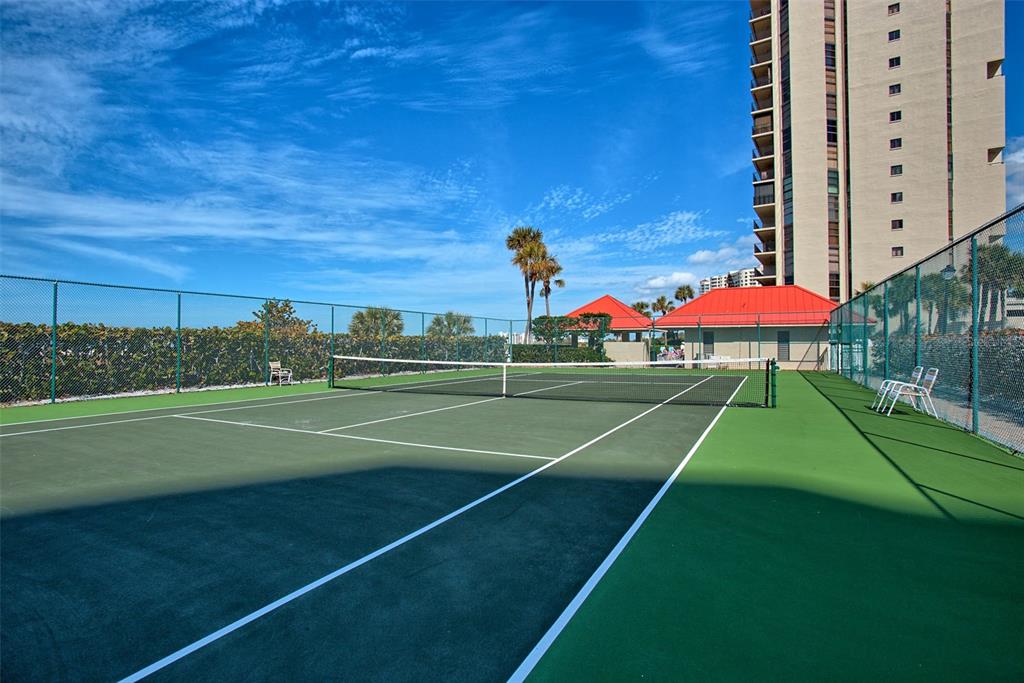 A balcony with patio furniture overlooks a sandy beach and the ocean under a blue sky — 1290 GULF BOULEVARD UNIT 903, CLEARWATER BEACH, FL