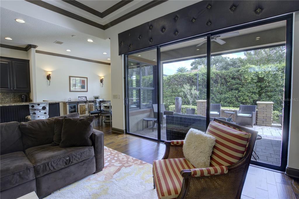 A living room features a dark sofa, a striped armchair, and sliding doors to a patio — 1219 GLENCREST DRIVE, LAKE MARY, FL