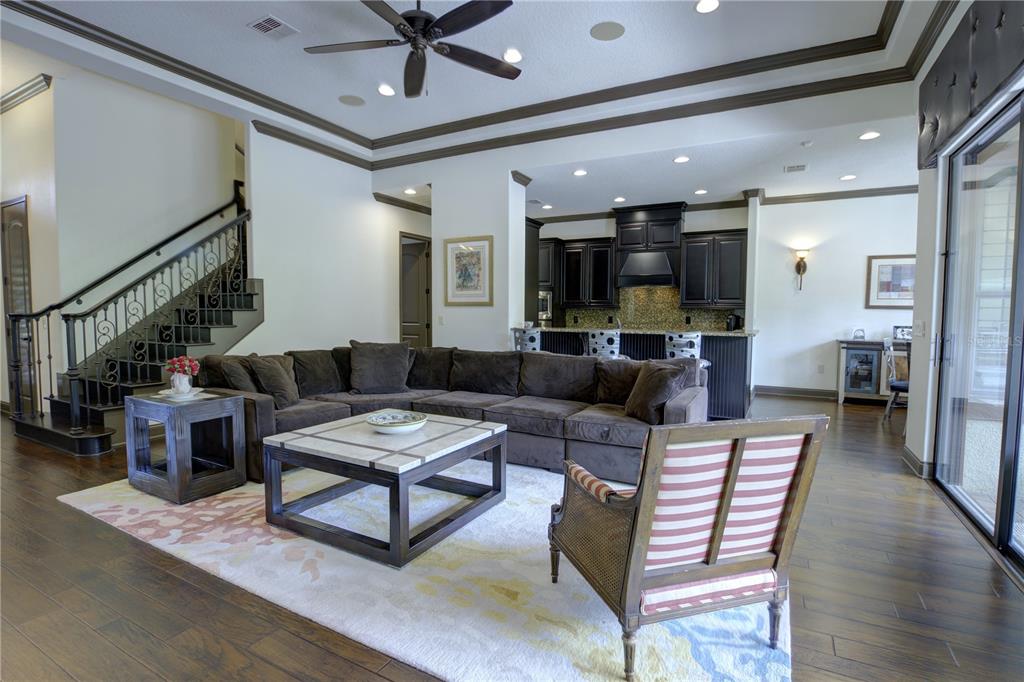 A living room with a sectional sofa, coffee table, and open kitchen with dark cabinetry — 1219 GLENCREST DRIVE, LAKE MARY, FL