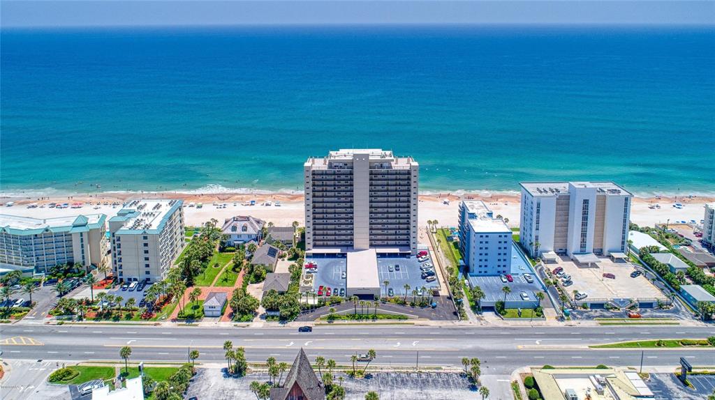 An aerial view shows a multi-story beachfront condominium complex situated between a road and the ocean — 89 S ATLANTIC AVENUE UNIT 204, ORMOND BEACH, FL