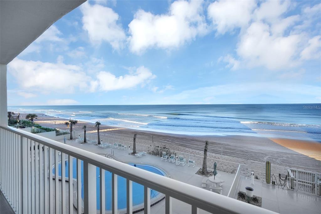 A balcony view overlooks a swimming pool, a sandy beach, and the ocean — 89 S ATLANTIC AVENUE UNIT 204, ORMOND BEACH, FL