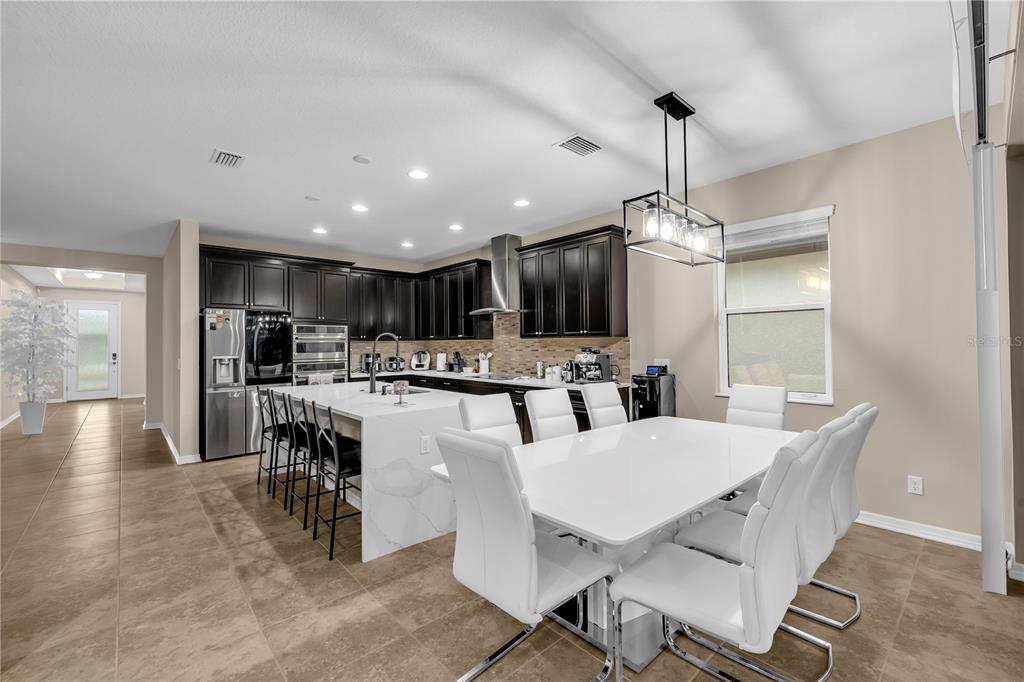A kitchen and dining area with dark cabinets, white countertops, and a white dining set — 1937 146TH TERRACE E, PARRISH, FL