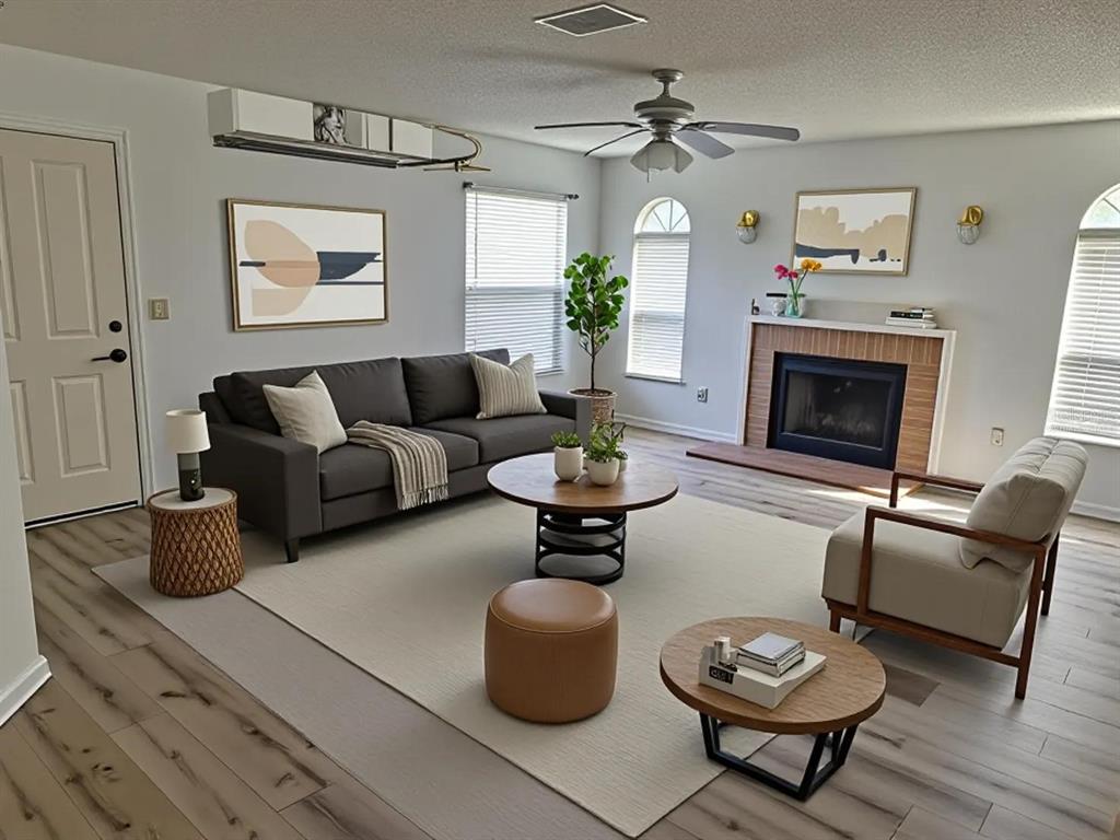 A living room features a dark sofa, a fireplace, two round coffee tables, and wood flooring — 11910 SKYLAKE PLACE UNIT E, TEMPLE TERRACE, FL