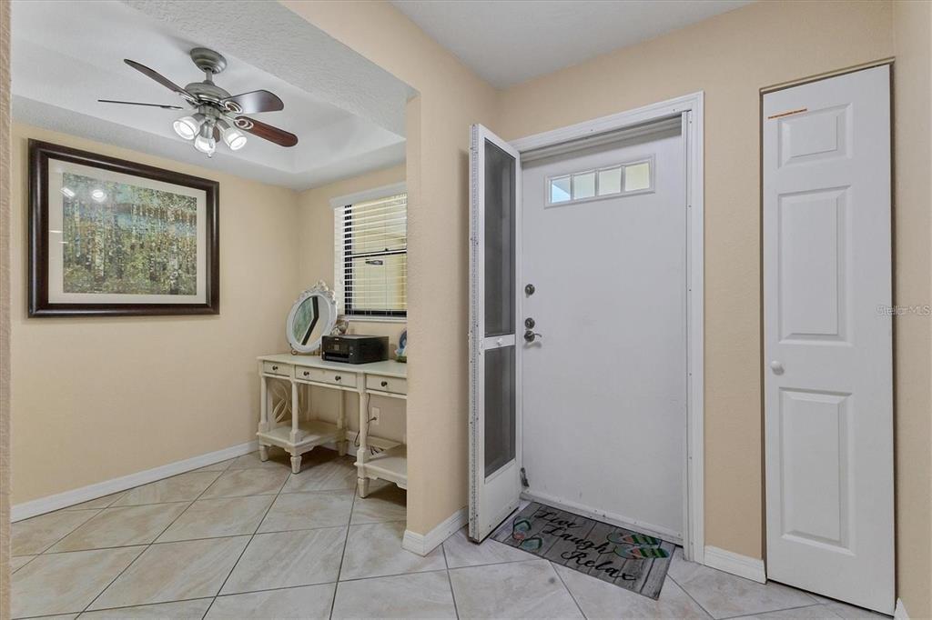 An entryway features a white door, tiled floors, a ceiling fan, and a console table — 8776 MIDNIGHT PASS ROAD UNIT C307, SARASOTA, FL