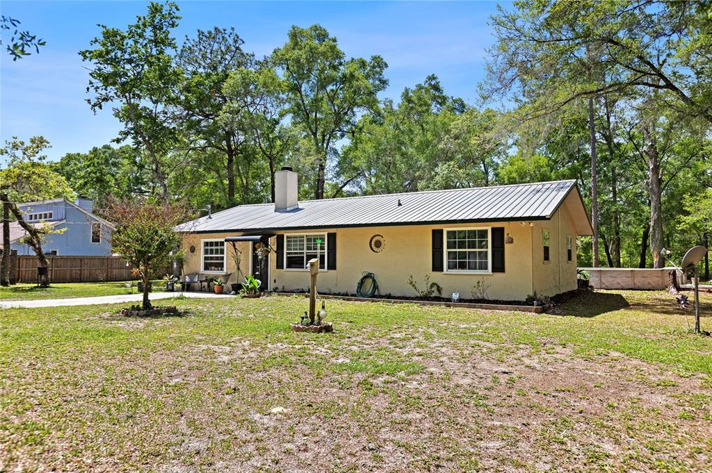 A single-story house with a metal roof and beige siding sits on a grassy lot — 5420 E GWENDOLYN PATH, INVERNESS, FL