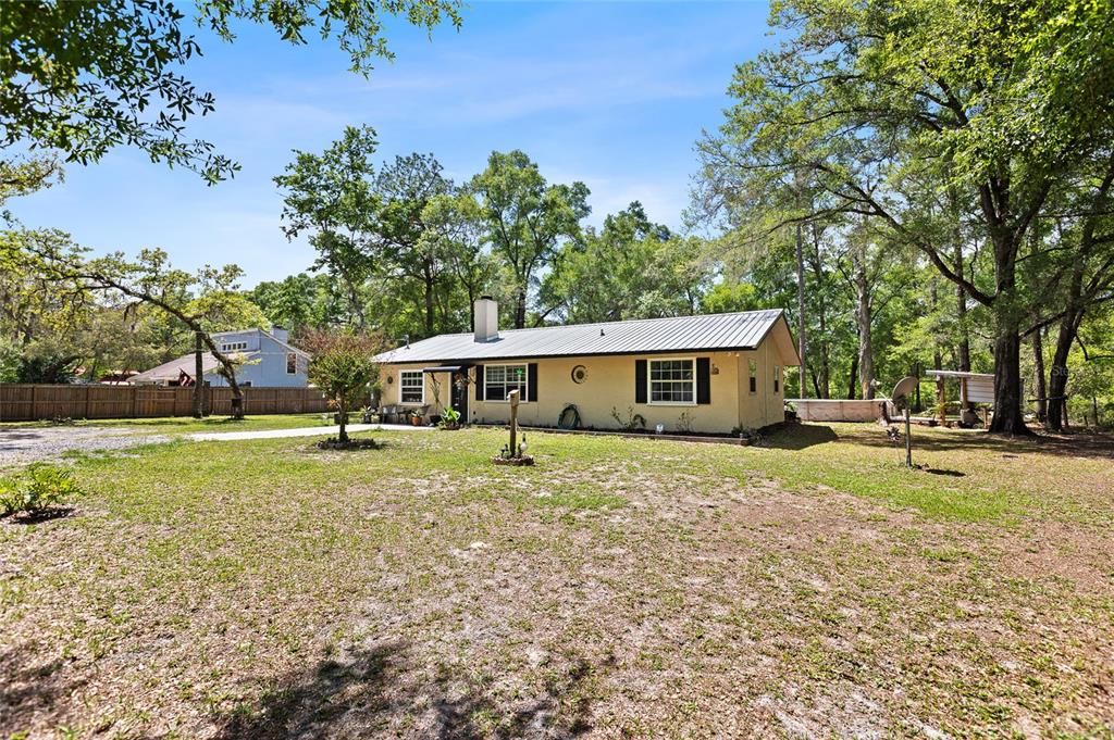A single-story, light-yellow house with a metal roof sits on a large, grassy lot — 5420 E GWENDOLYN PATH, INVERNESS, FL