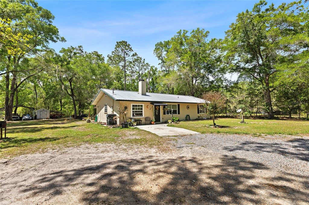 A single-story house with a metal roof sits on a large, wooded lot — 5420 E GWENDOLYN PATH, INVERNESS, FL