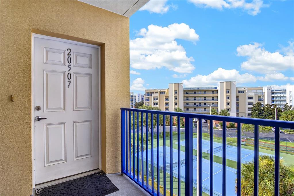 An exterior view of a white apartment door with number 20507 overlooking a tennis court — 5300 S ATLANTIC AVENUE UNIT 20507, NEW SMYRNA BEACH, FL