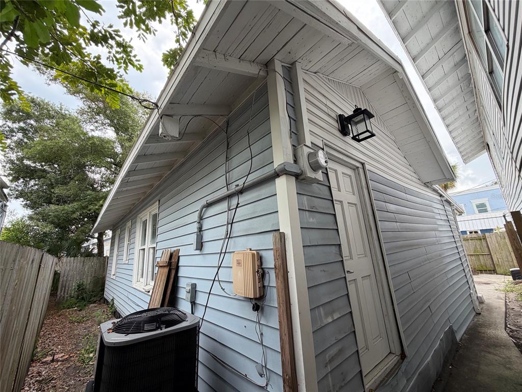 Exterior view of a light blue house with an AC unit, utility boxes, and a door — 618 15TH STREET N, ST PETERSBURG, FL