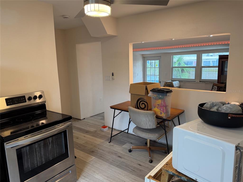 A kitchen with stainless steel appliances, wood-look flooring, and a pass-through window to another room — 618 15TH STREET N, ST PETERSBURG, FL