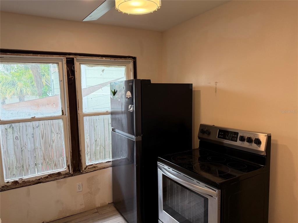A kitchen features a black refrigerator, a black electric stove, and a window with trim — 618 15TH STREET N, ST PETERSBURG, FL
