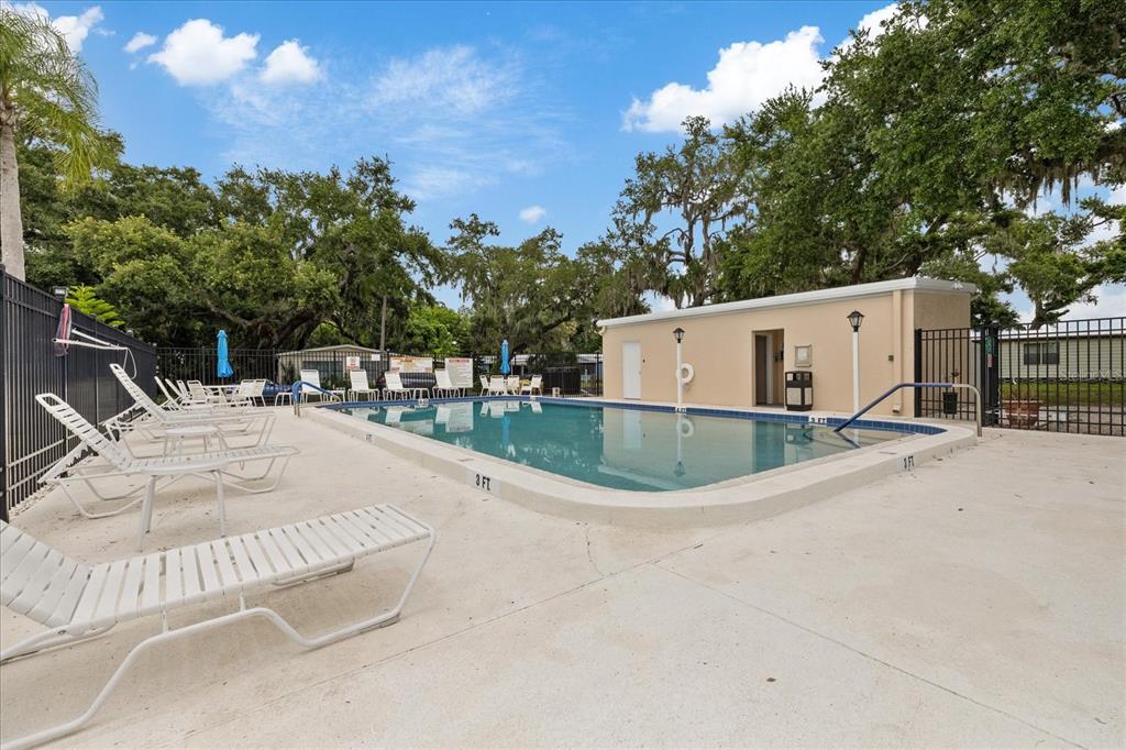 An outdoor swimming pool surrounded by lounge chairs and trees under a blue sky — 3405 FLORENCE DRIVE, ELLENTON, FL