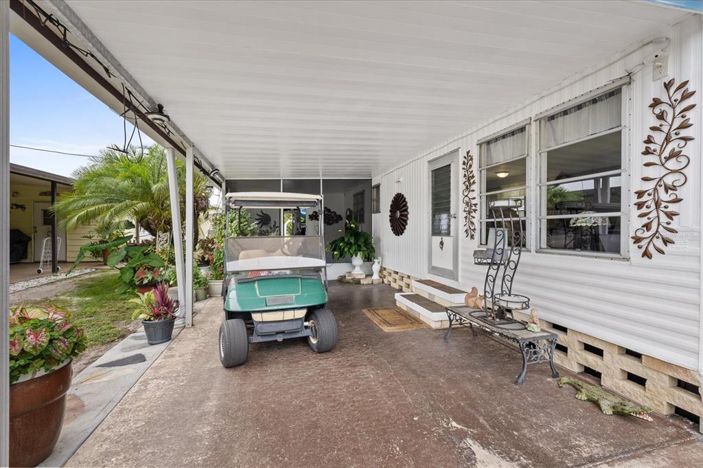 A covered carport features a golf cart parked in front of a mobile home exterior — 3405 FLORENCE DRIVE, ELLENTON, FL