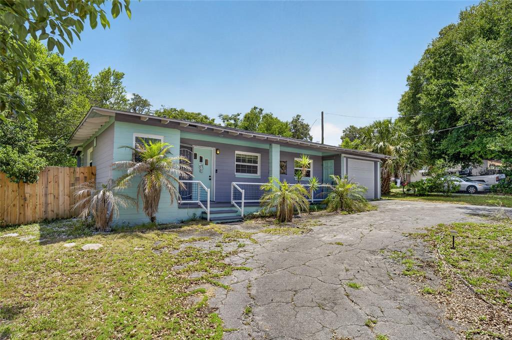 A single-story house with a teal and gray exterior features a driveway and palm trees — 129 COLOMBA ROAD, DEBARY, FL