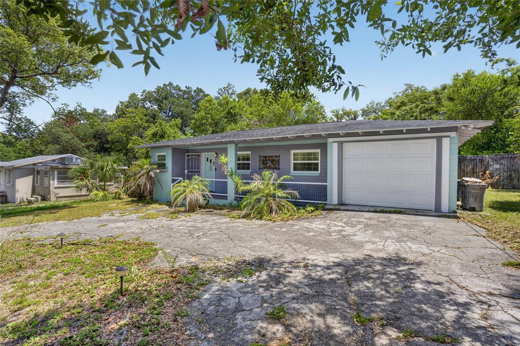 A single-story house with a gray exterior, a white garage door, and a cracked concrete driveway — 129 COLOMBA ROAD, DEBARY, FL