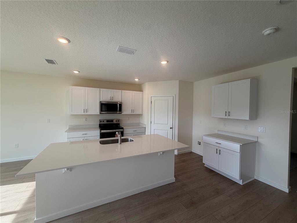 A dining area with a wooden table and chairs sits beside an entryway with flooring — 1640 HOUMAS STREET, ORMOND BEACH, FL