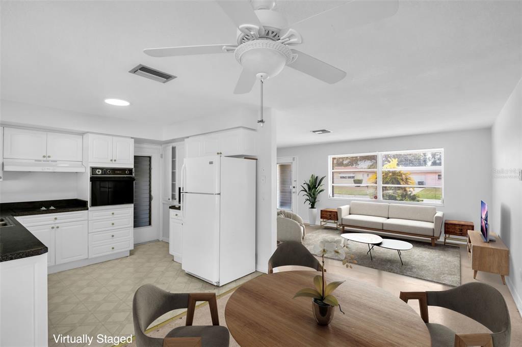 A kitchen with white cabinets and a white refrigerator opens into a living room area — 2301 WHITMAN STREET, CLEARWATER, FL