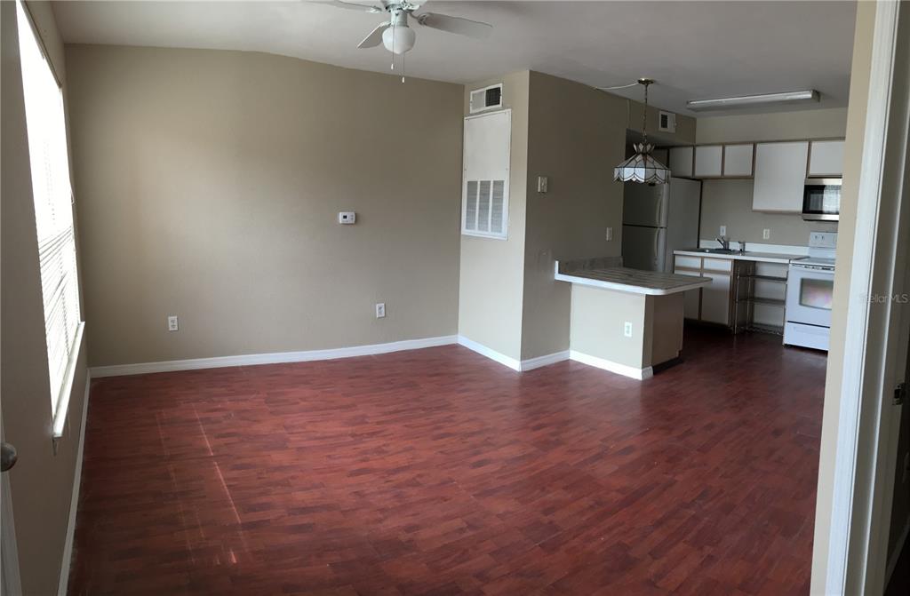 An open-concept living area features wood-look flooring, a ceiling fan, and an adjacent kitchen — 2200 KEY WEST COURT UNIT 723, KISSIMMEE, FL