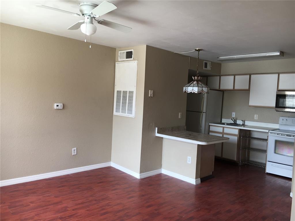 An open-concept kitchen and living area feature wood-look flooring, white cabinets, and a ceiling fan — 2200 KEY WEST COURT UNIT 723, KISSIMMEE, FL