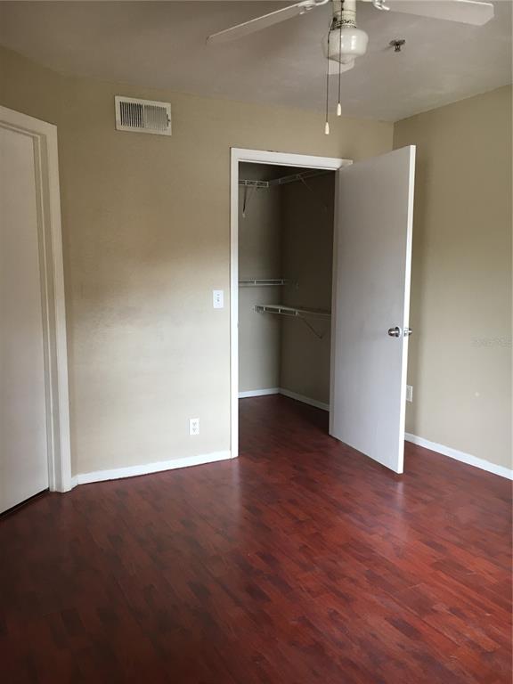 A bedroom with wood-look flooring, a ceiling fan, and an open walk-in closet — 2200 KEY WEST COURT UNIT 723, KISSIMMEE, FL