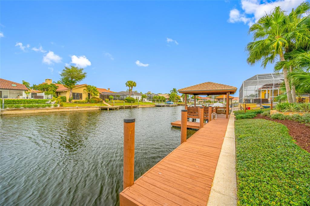 A wooden dock with a covered gazebo extends into a canal beside a residential backyard — 9807 COMPASS POINT WAY, TAMPA, FL