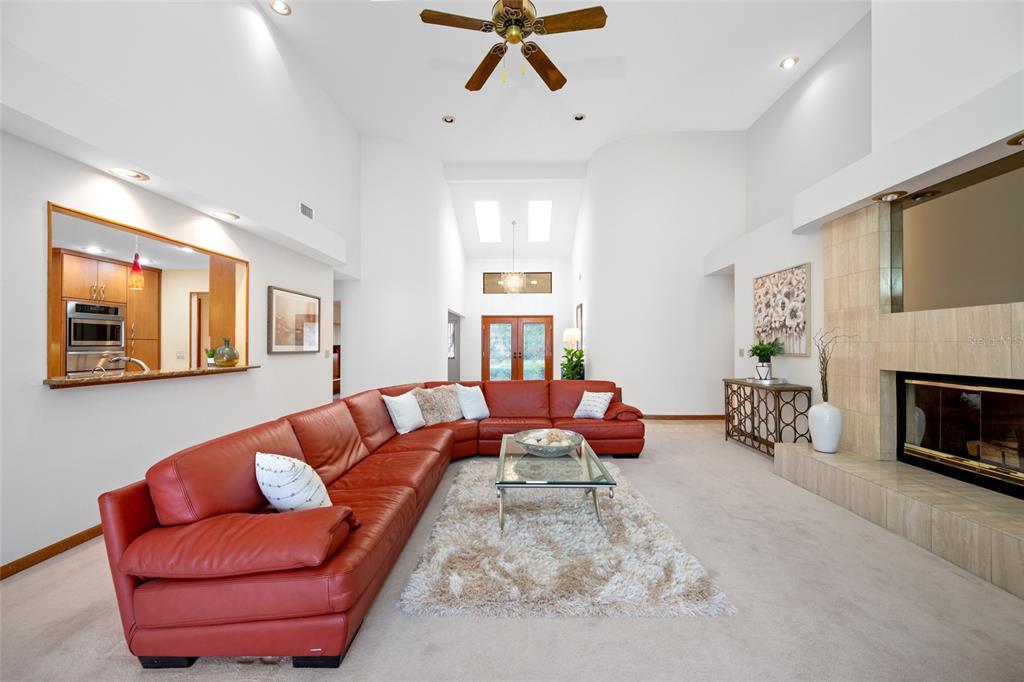 A spacious living room features a large red sectional sofa, a fireplace, and vaulted ceilings — 9807 COMPASS POINT WAY, TAMPA, FL